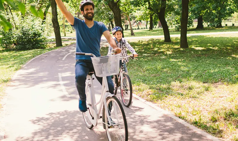 Father and child cycling along a tree-lined track near Fairway Villas 3 in Emaar South, Dubai.